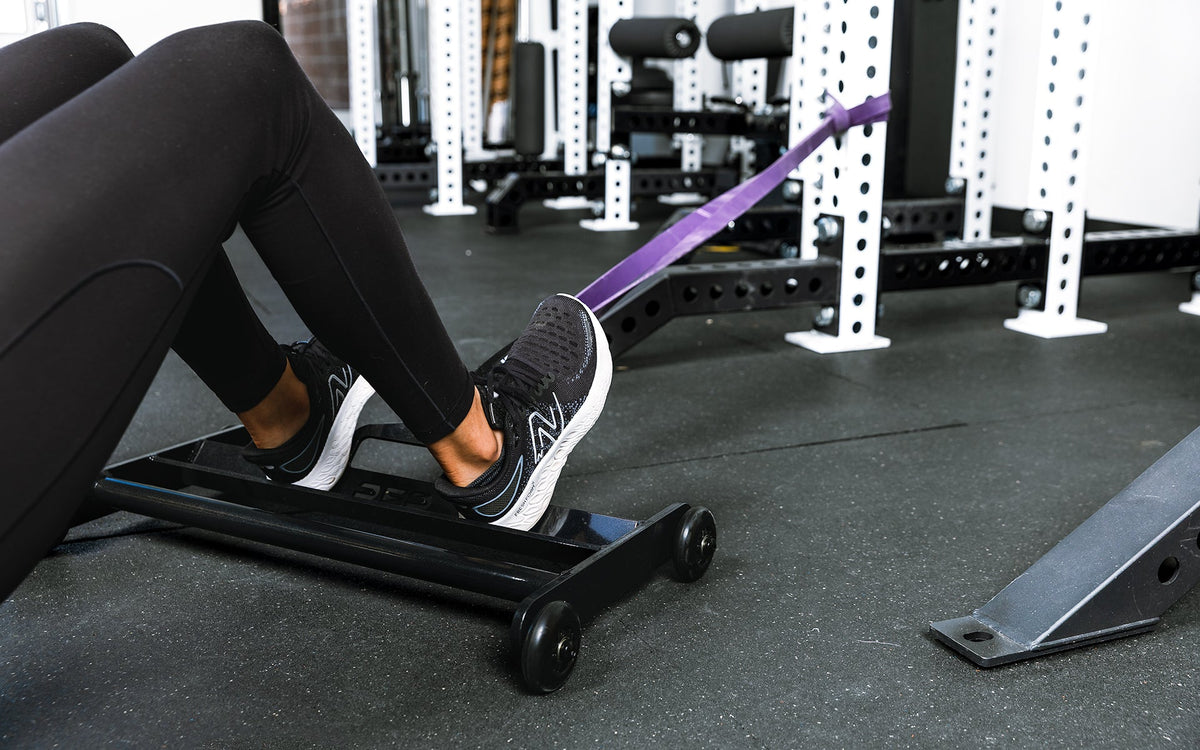 Athlete using glute ham roller with bands attached to a rack
