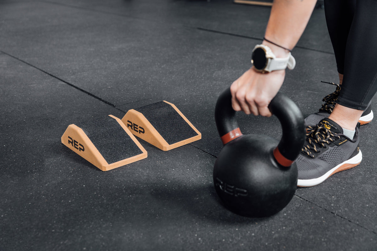 Athlete lifting a kettlebell next to Cork Squat Wedges