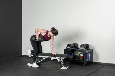An athlete doing dumbbell rows on a Nighthawk bench with the Quickdraw adjustable dumbbells