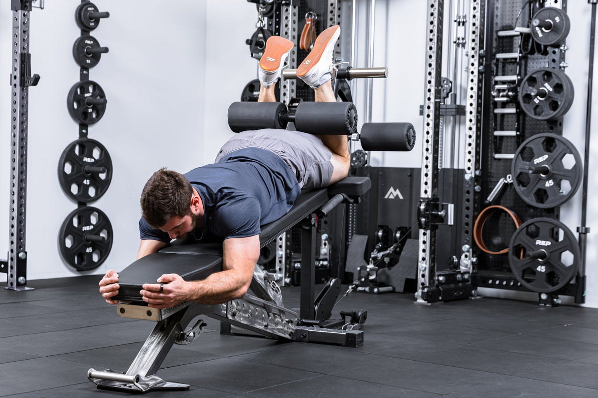 Athlete using cable resistance to do hamstring curls on theLeg Extension & Leg Curl Bench Attachment