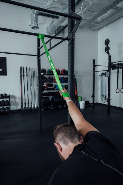 Athlete stretching with a green Latex-Free Pull-Up Band.