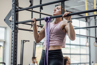 Athlete using a purple Latex-Free Pull-Up Band for assistance while performing pull-ups.