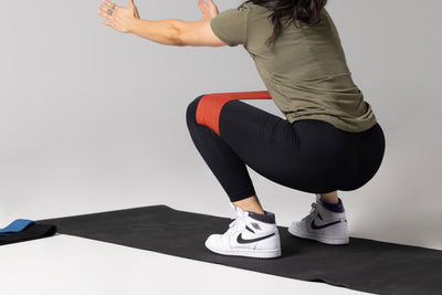 Lifter performing an air squat using the red light resistance REP circle hip band.
