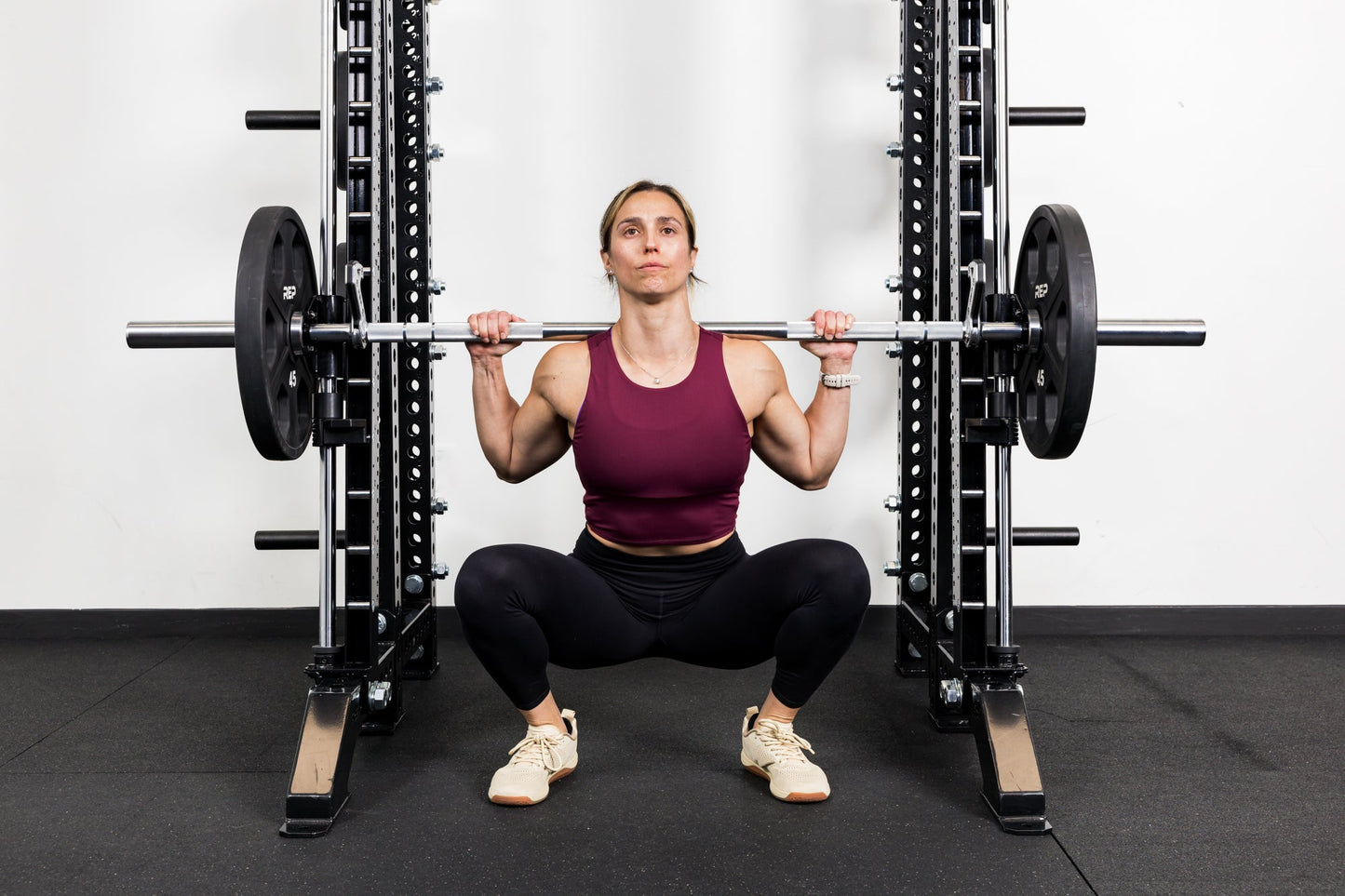 Athlete squatting on the front of a rack mounted Smith Machine