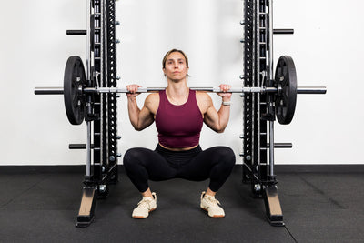 Athlete squatting on the front of a rack mounted Smith Machine
