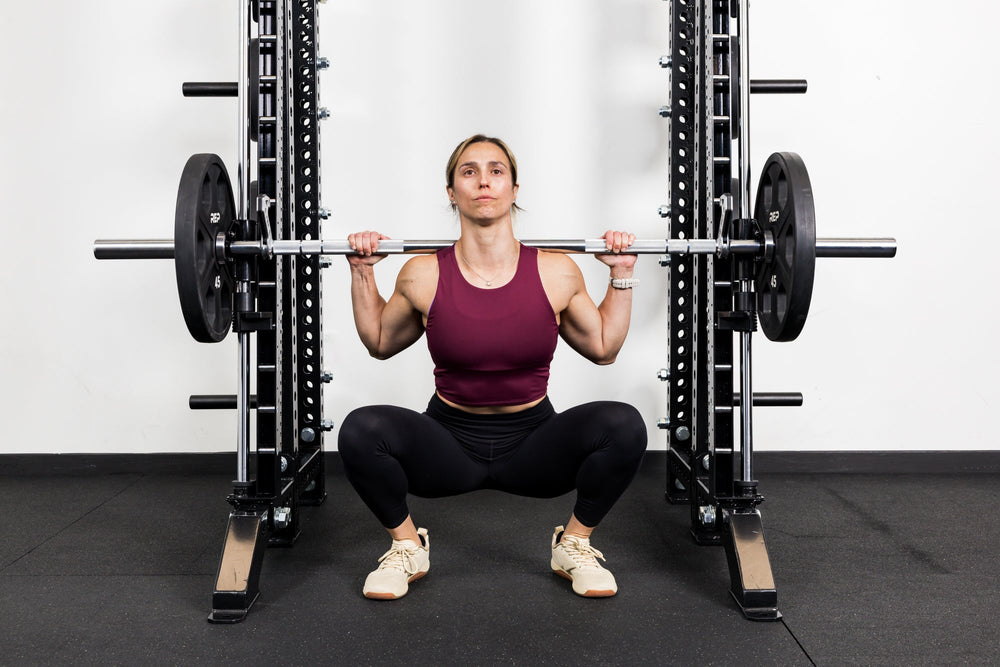 Athlete squatting on the front of a rack mounted Smith Machine