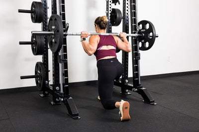 Athlete doing split squats on the front of a rack mounted Smith Machine
