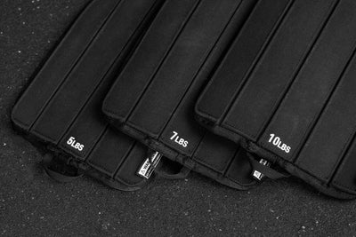 Black soft weight vest plates with weight markings on a dark background