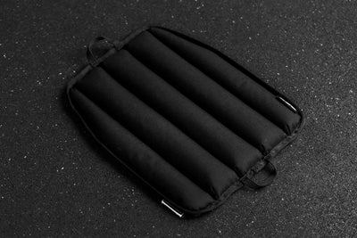 Black soft weight vest plate with ribbed texture on a dark textured background