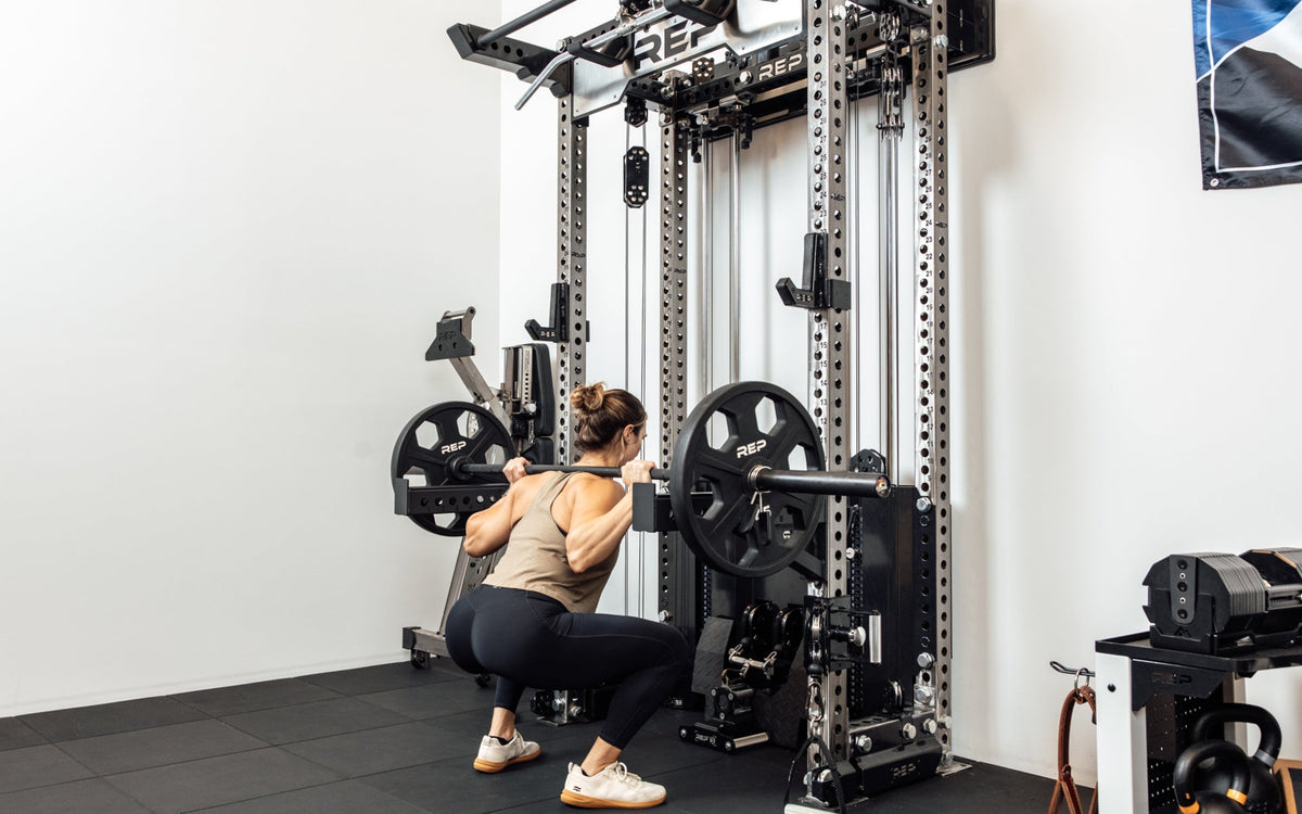 An athlete performing barbell squats off the front of the Wall-Mounted Ares™ 2.0 with spotter arms