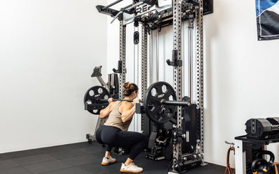 An athlete performing barbell squats off the front of the Wall-Mounted Ares™ 2.0 with spotter arms