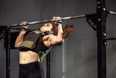Athlete wearing the olive Strata Weight Vest doing pull-ups