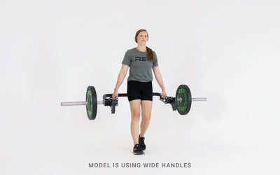 Lifter performing a walking carry using the Open Trap Bar with wide handles.