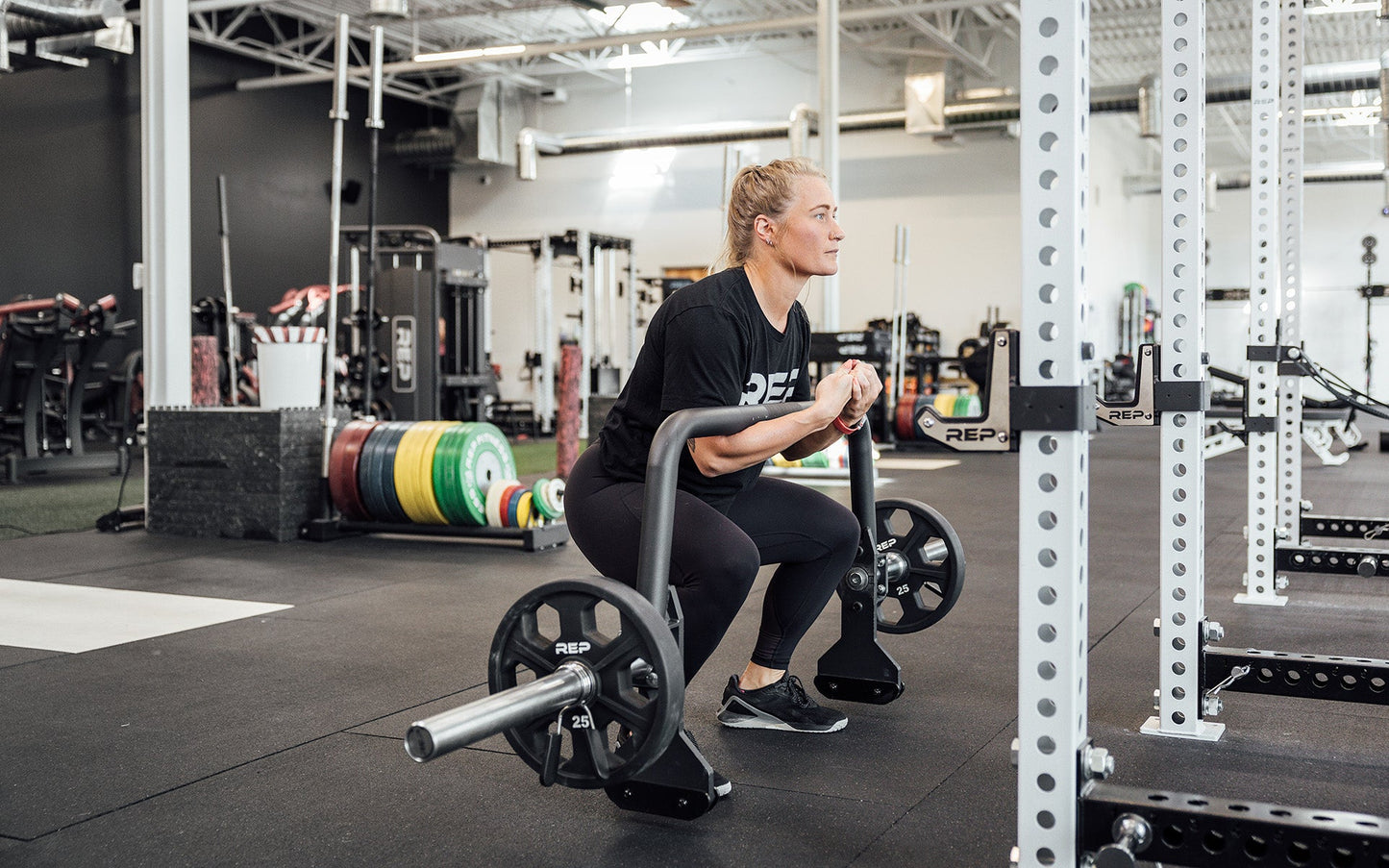 Female athlete performing a zercher squat with the REP Open Trap Bar.
